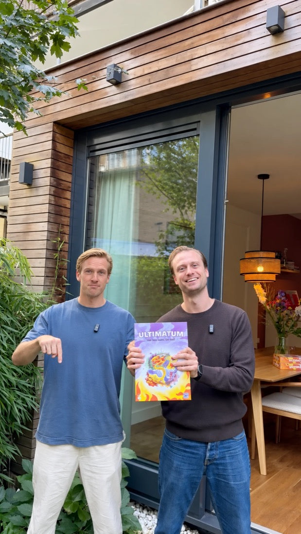 Paul en Abe voor een huis met de doos van Ultimatum in hun handen